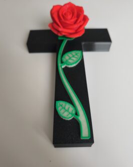 Croix commémorative avec rose rouge et tige lumineuse dans l’obscurité